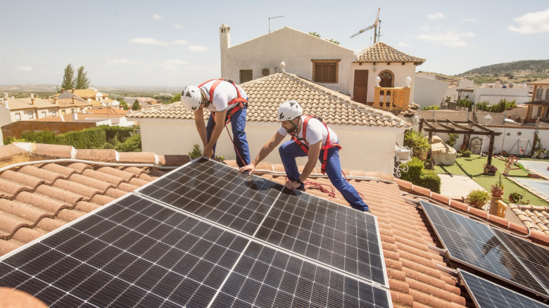 Workers installing solar panels on the roof of a house