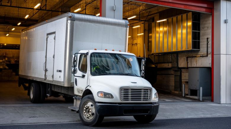 The moving truck with a box trailer leaves the gate of a multistory building after unloading the moving boxes