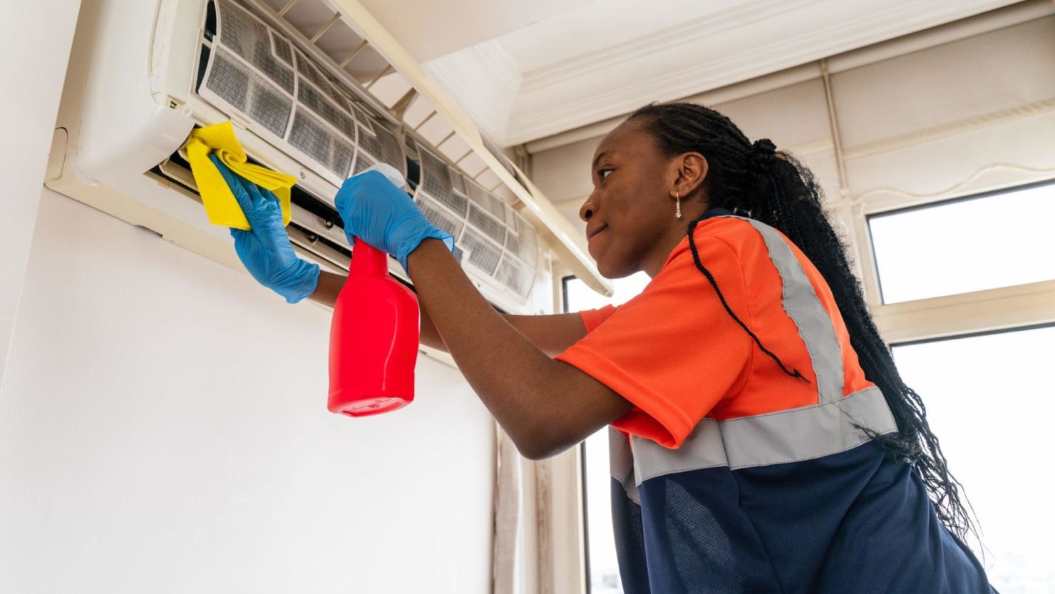 Woman cleaning and repairing a ductless air conditioning unit