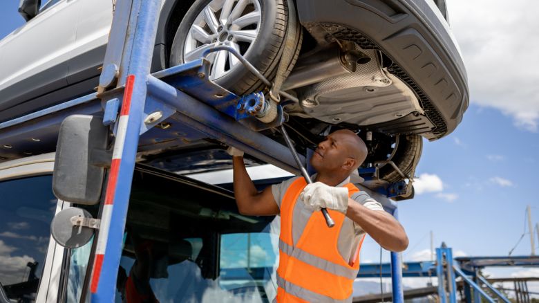 Car transport driver tightening the carrier before getting on the road.