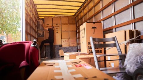 Mover securing boxes to the back of a moving truck. 