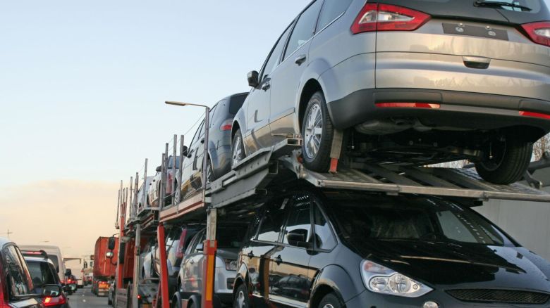 A truck with an open carrier transporting vehicles.