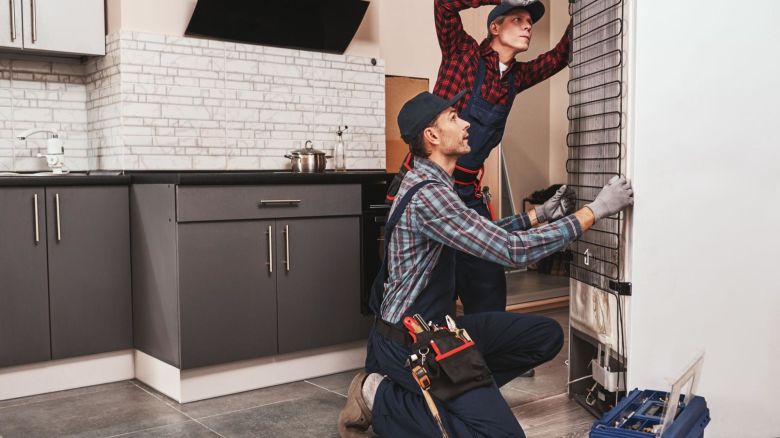 Two service repair workers fixing a refrigerator.