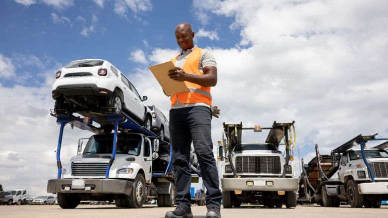 Auto transport worker checking a clipboard before departure.