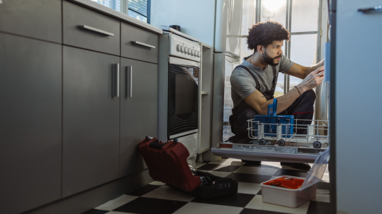 Service technician fixes a dishwasher for the homeowner.