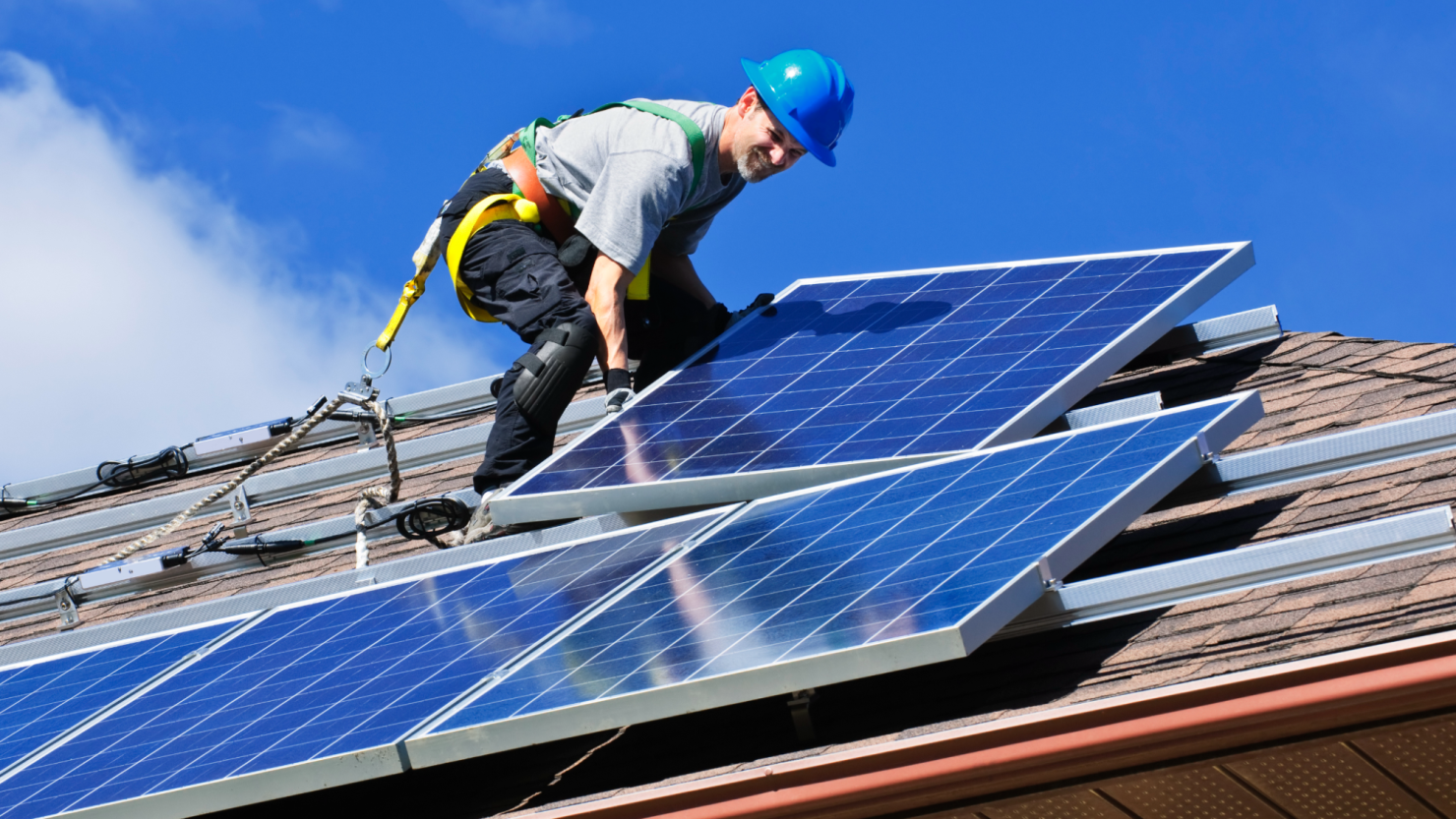 Technician installing photovoltaic solar panels on a roof