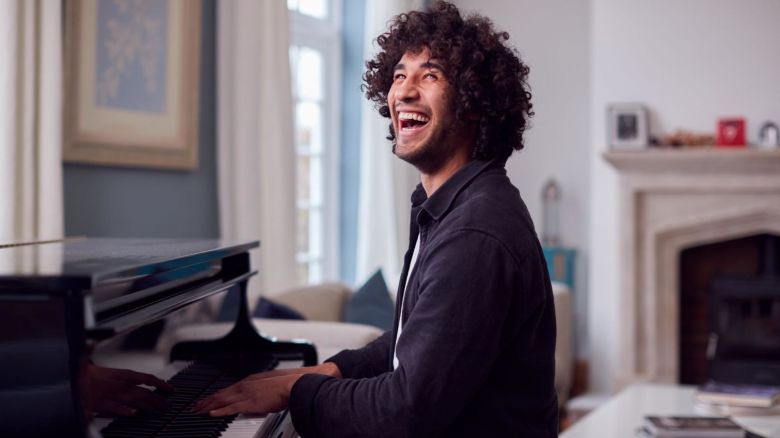 Homeowner playing a piano and laughing.