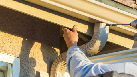 Worker installs a gutter on a home.