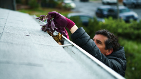 Person cleaning gutters