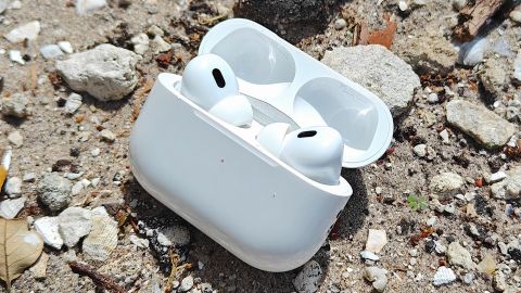 An open AirPods Pro case on a rocky surface.
