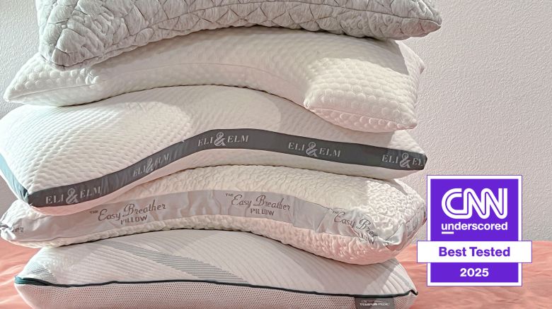 A pile of side sleeper pillows on a bed.