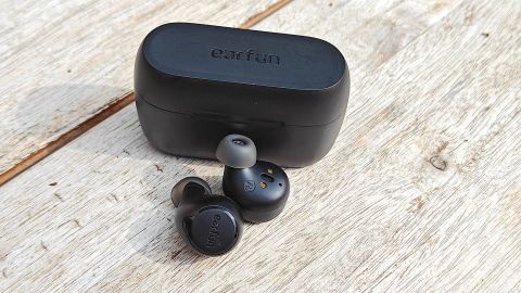 The EarFun Free 2S earbuds and their case on a wooden surface.