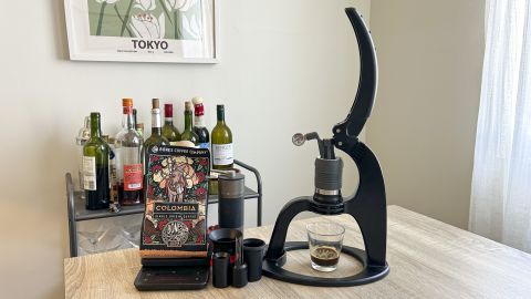 Flair Neo Flex manual espresso maker next to coffee grinder and bag of coffee beans