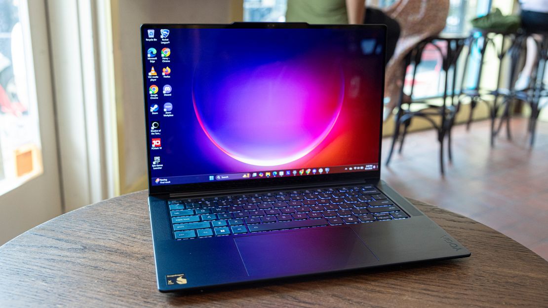 Lenovo yoga slim 7x on a small table with a purpleish desktop background