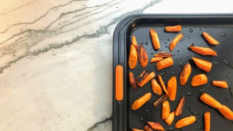 The Le Creuset Large Sheet Pan, with roast carrots, on a marble countertop