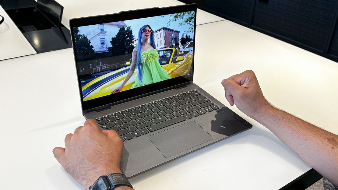 The Lenovo IdeaPad Slim 5x 2-in-1 is playing the music video for Charly Bliss' "Back There Now" with Eva Hendricks in a neon green dress. Hands are in front of the laptop