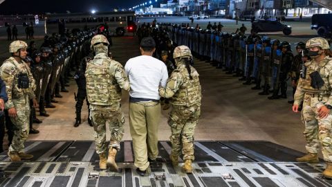 Personal militar estadounidense escolta a un presunto pandillero que fue deportado por Estados Unidos junto con otros que Estados Unidos alega son de la pandilla venezolana Tren de Aragua y la pandilla MS-13 en el Aeropuerto Internacional de El Salvador en San Luis Talpa, El Salvador, el 12 de abril de 2025.