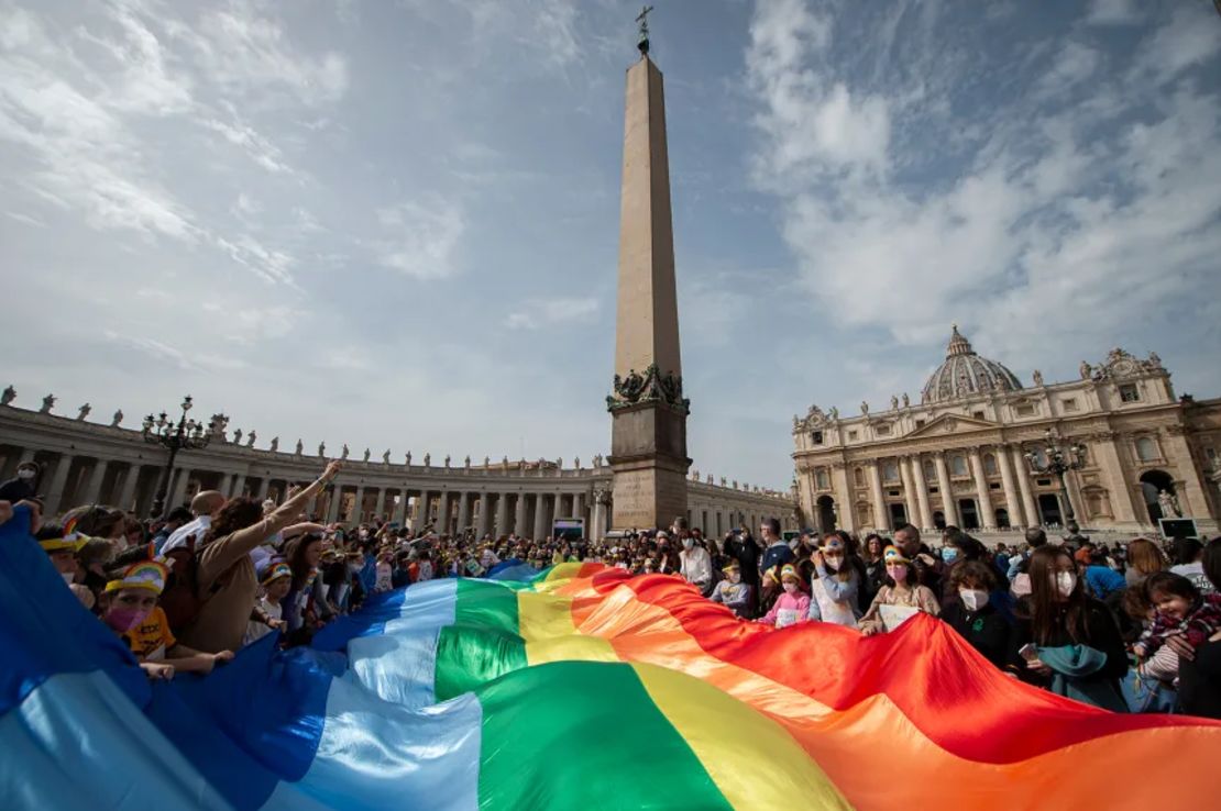 Niños sostienen una bandera arcoíris mientras el papa Francisco se dirige a la multitud durante su oración del Ángelus desde la ventana del palacio apostólico con vista a la Plaza de San Pedro, Vaticano, el 27 de marzo de 2022.