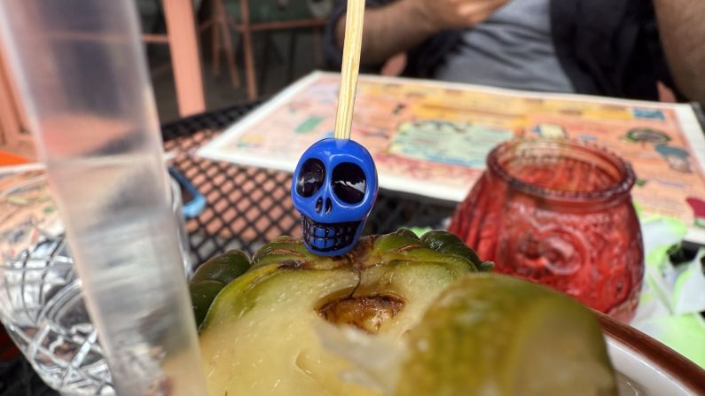 a blue skull is attached to the top of a pineapple wedge in a drink