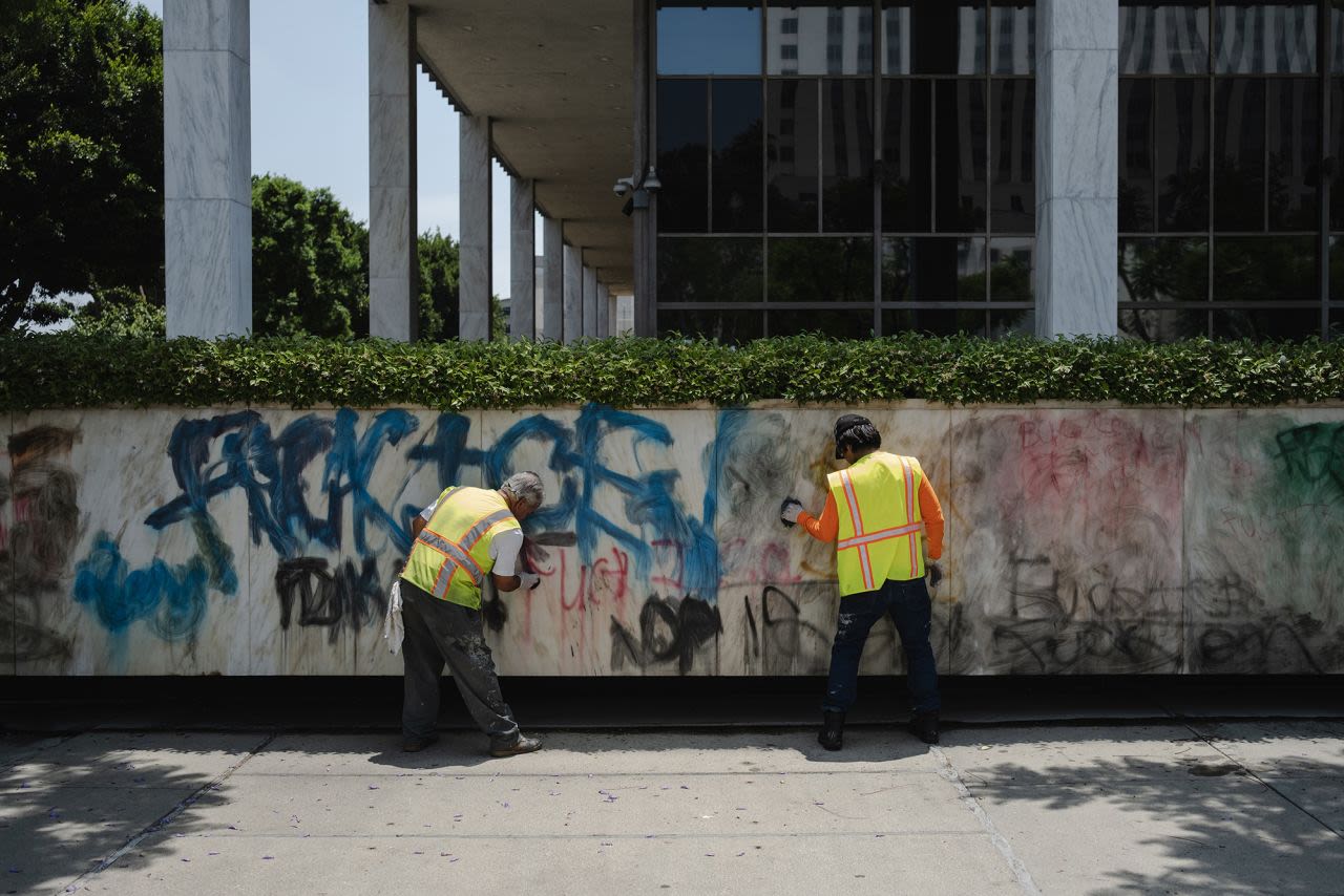 Hombres limpian grafitis en el lateral del Edificio Federal Robert Young en el centro de Los Ángeles el lunes.