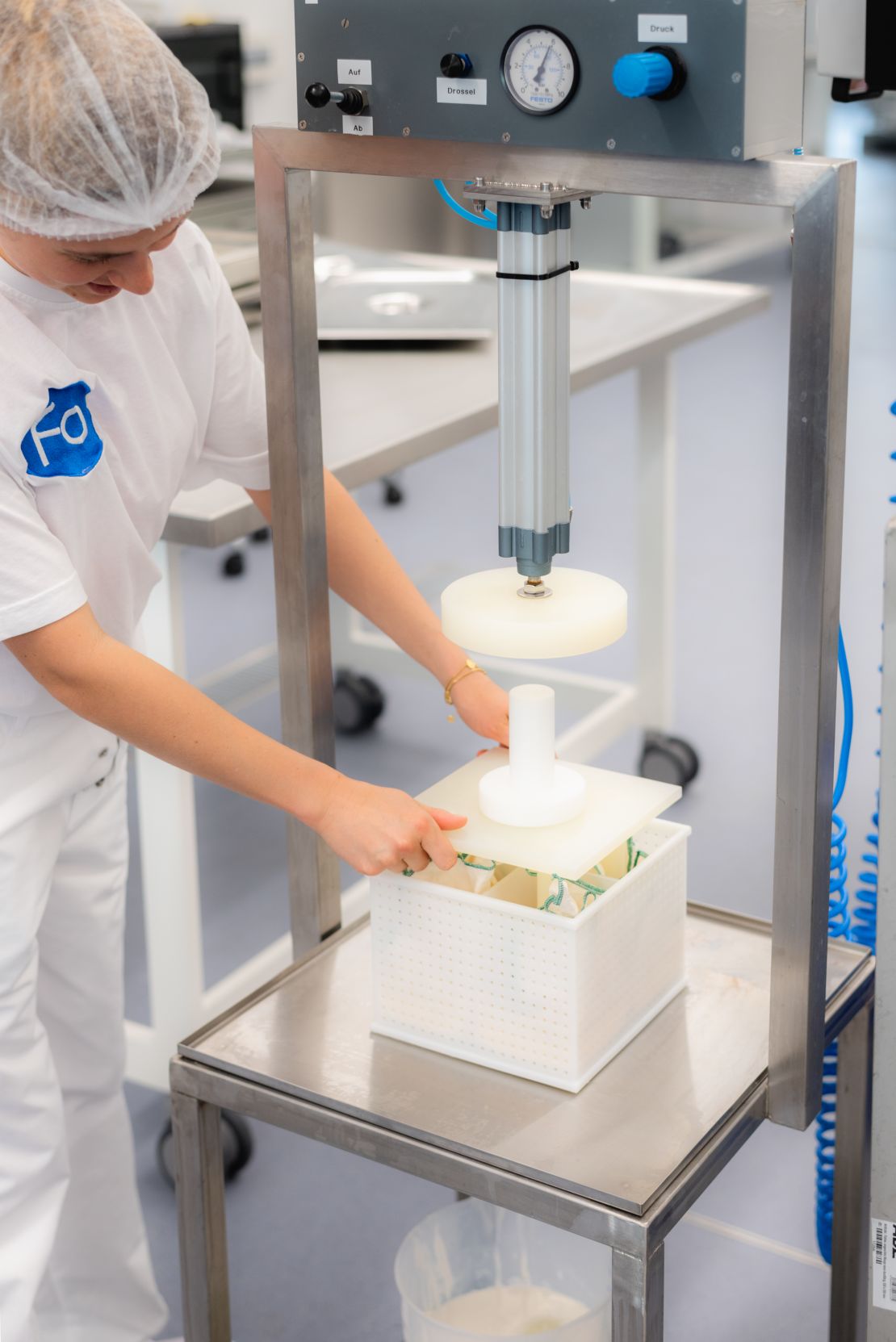 A member of the Formo team uses a cheese press to mold cheese made using micro-fermentation technology.