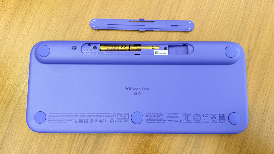 the lilac purple logitech pop icon keys keyboard from below with battery door open and AAA batteries exposed