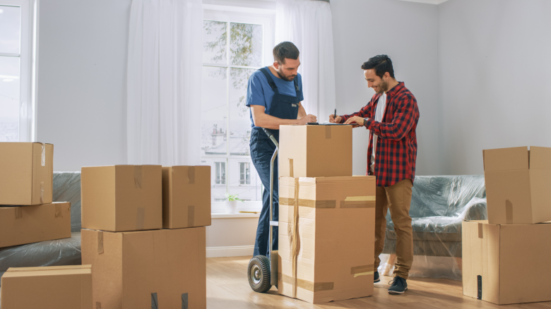 Professional movers carrying in new furniture in a cardboard box