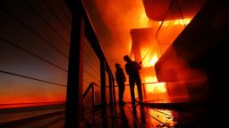 Los bomberos trabajan desde una terraza mientras el incendio Palisades quema una propiedad frente a la playa en Malibu el 15 de enero de 2025.