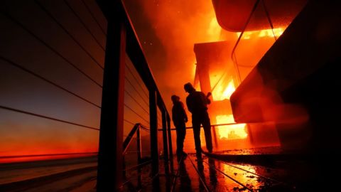 Los bomberos trabajan desde una terraza mientras el incendio Palisades quema una propiedad frente a la playa en Malibu el 15 de enero de 2025.