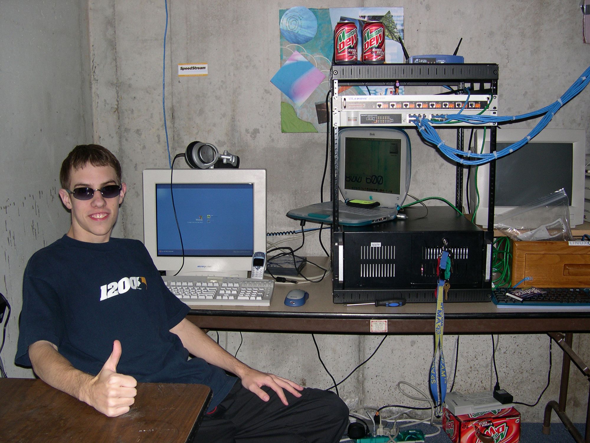 An array of electronics, cables, soda cans — and shades; the quintessential LAN party set-up as pictured in a gamer's basement space in Lee's Summit, Montana in 2002.