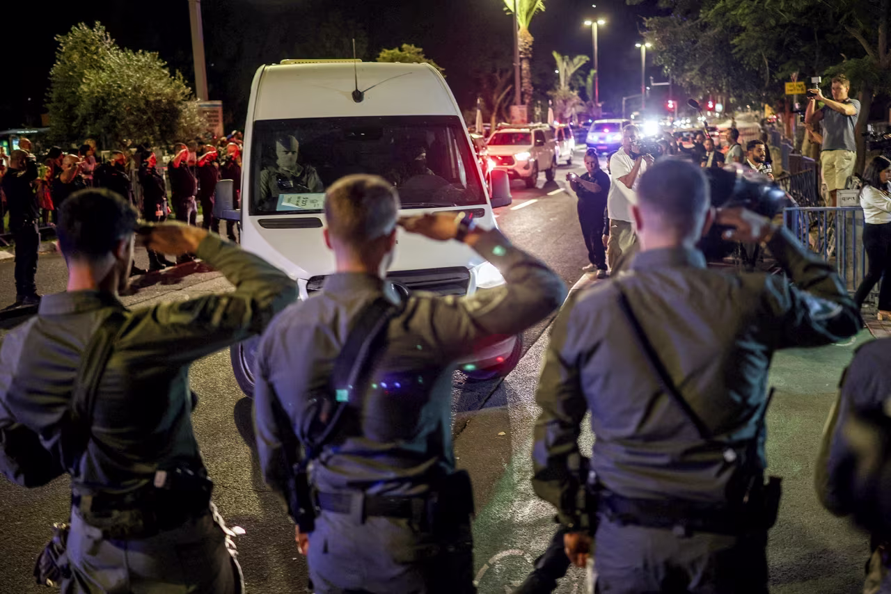 Policías israelíes saludan cuando vehículos que transportan los cuerpos de cuatro rehenes fallecidos llegan a un instituto forense en Tel Aviv, Israel, el lunes.