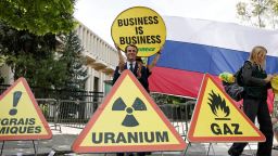 Activistas fotografiados con carteles protestando contra las políticas del presidente francés, Emmanuel Macron, hacia Rusia.