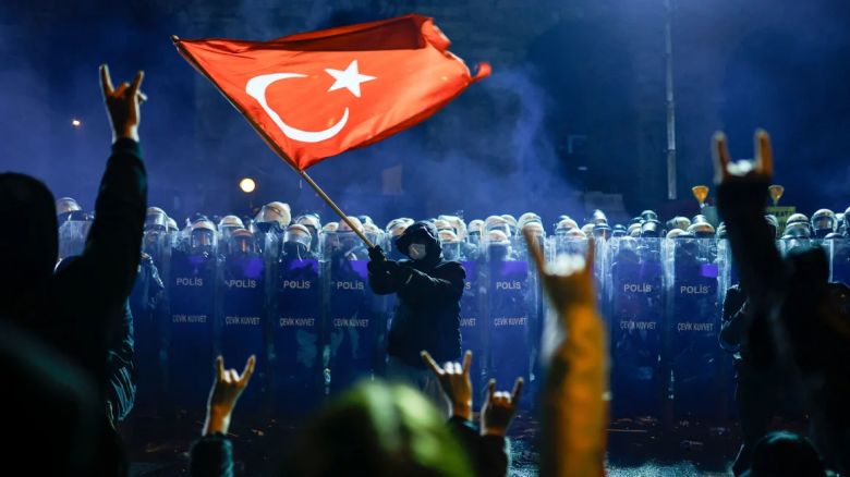 Un manifestante ondea la bandera nacional de Turquía ante la policía antidisturbios turca, mientras los manifestantes se manifiestan frente al ayuntamiento de Estambul para apoyar al alcalde de Estambul, Ekrem Imamoglu, en Estambul, el sábado.<br /><br />