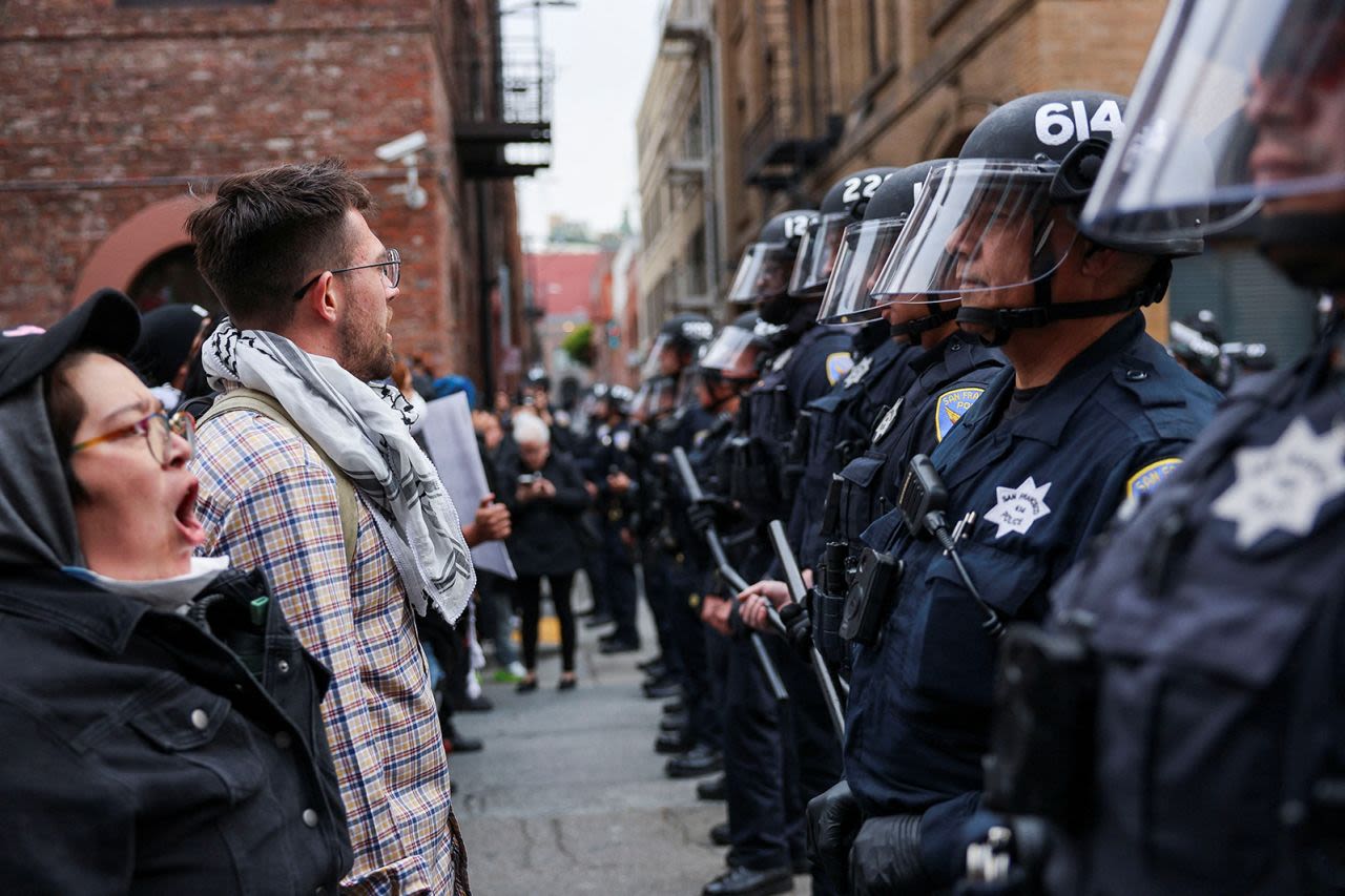Los manifestantes se paran frente a agentes de policía mientras se reúnen durante una protesta contra las redadas federales de inmigración en el edificio de ICE en San Francisco, California, el domingo