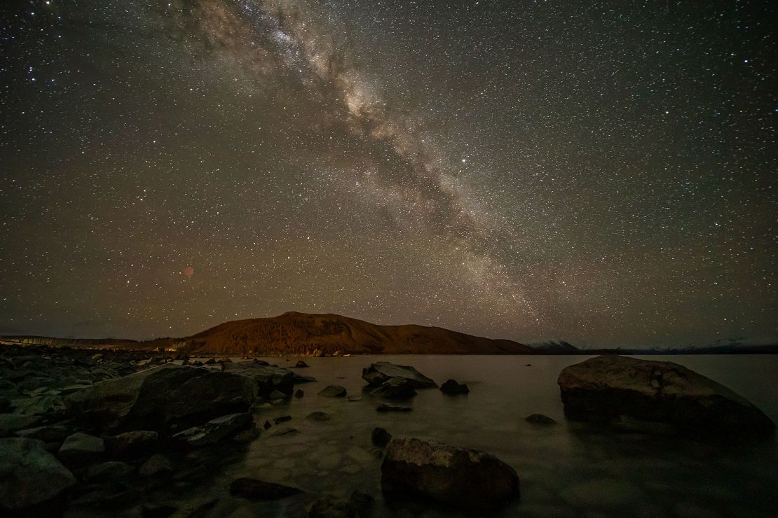 The Milky Way appears in the sky above Lake Takapō in the Mackenzie Country, South Island, New Zealand.