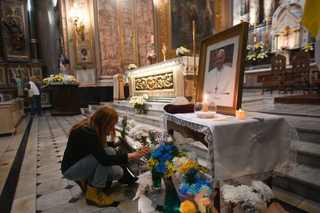 Una mujer coloca flores bajo una fotografía del difunto papa Francisco en la Basílica de San José de Flores. Se están dejando homenajes en honor al difunto pontífice por todo Buenos Aires, en lugares que fueron especiales para él.