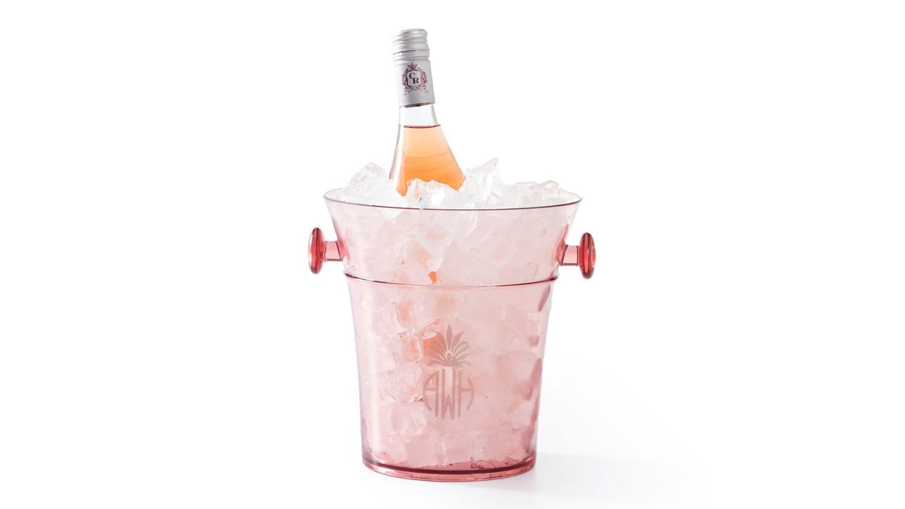 A pink ice bucket filled with ice and a bottle of wine.