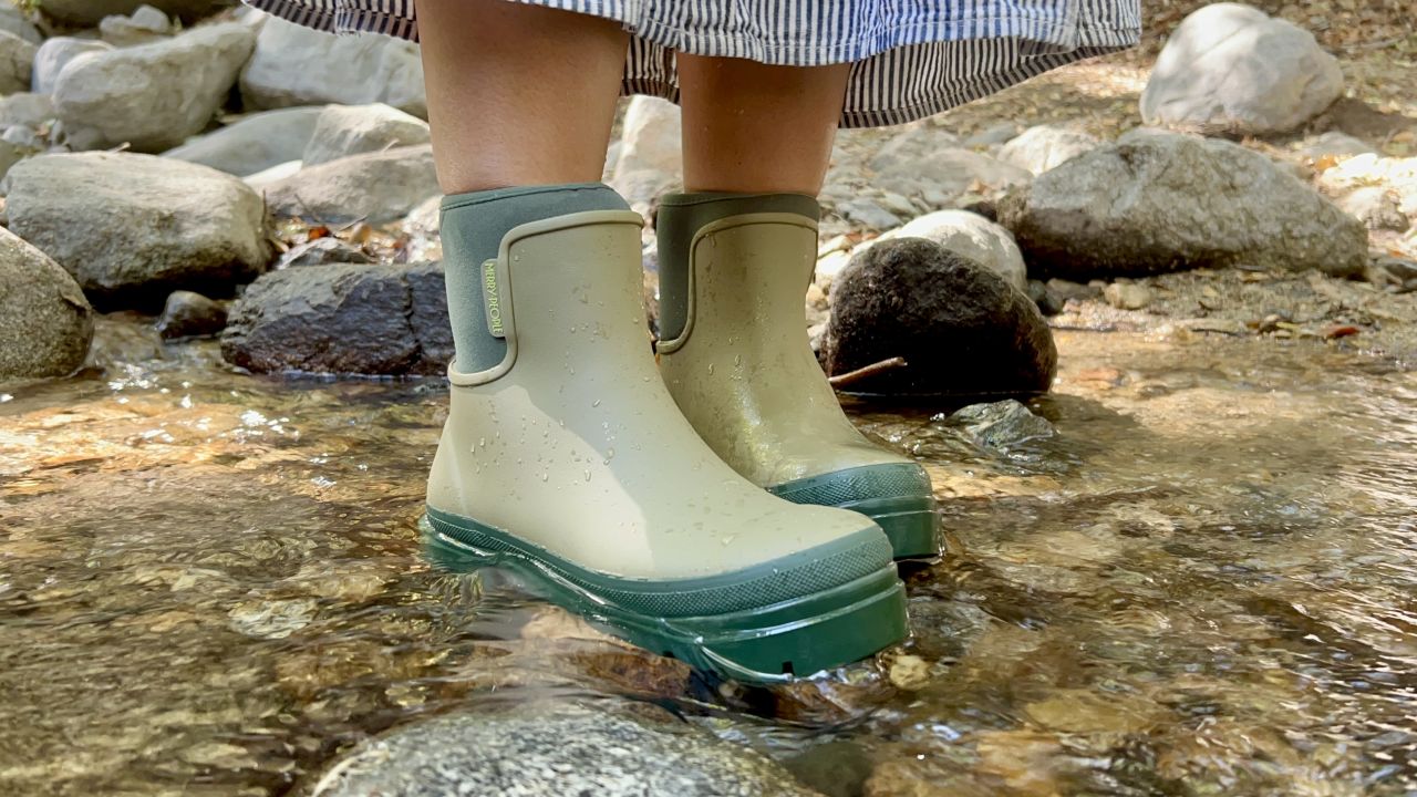 Person wearing green rain boots in a river.