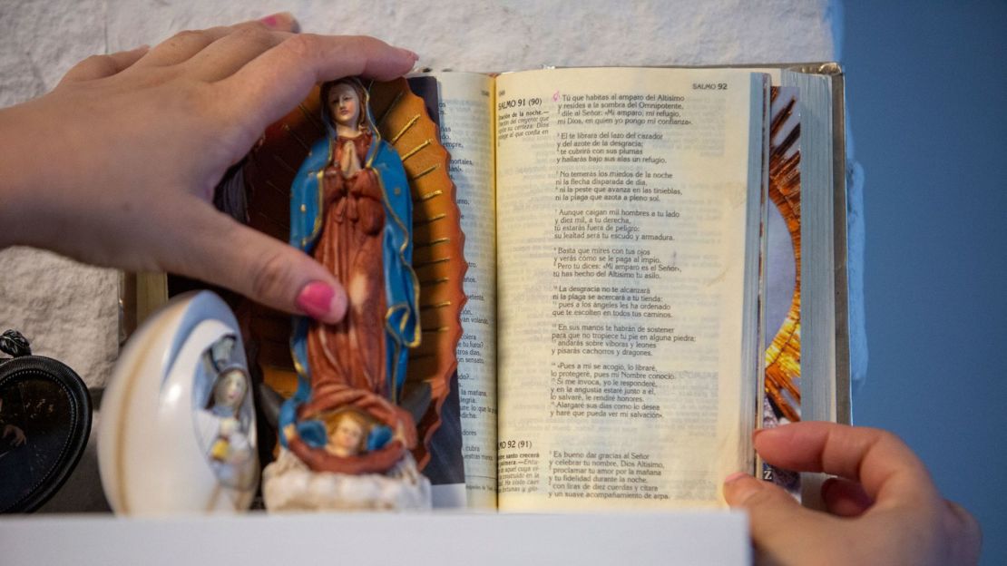 Una estatua de Nuestra Señora de Guadalupe y una biblia se encuentran en la repisa de la casa de Susana. Su madre las trajo cuando los visitó desde México. La biblia está abierta en una oración de protección.