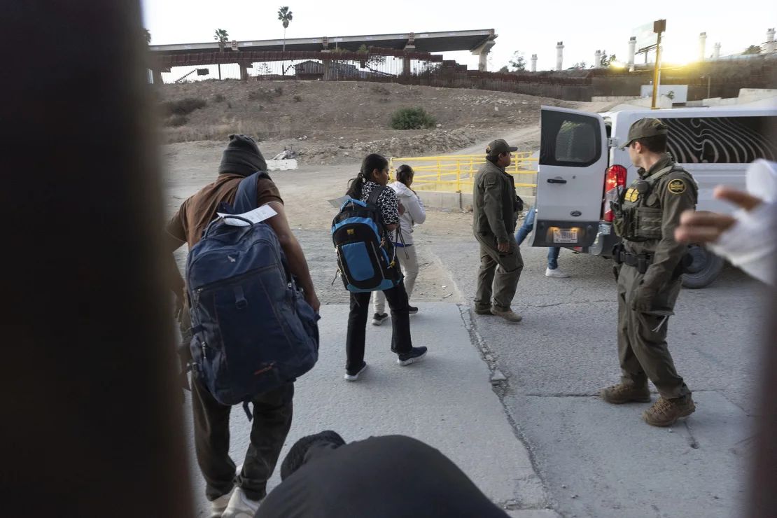Los migrantes se dirigen a una camioneta de la Patrulla Fronteriza en San Diego el martes después de cruzar ilegalmente y esperar para solicitar asilo entre dos muros fronterizos que separan a México y Estados Unidos.