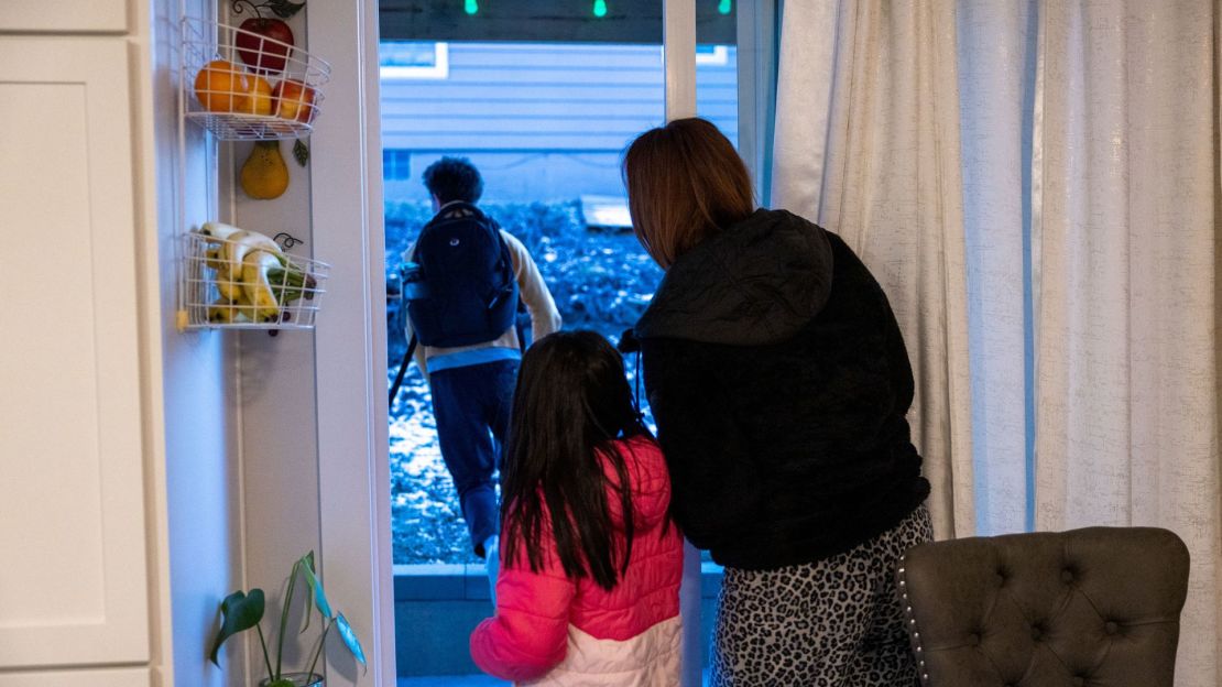 Andrés, de 13 años, sale corriendo por la puerta para tomar el autobús escolar mientras Susana y Jessica observan. Hace varios años, salió corriendo por la misma puerta para escapar del incendio que destruyó su hogar.