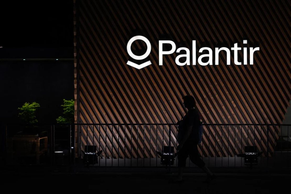 Una mujer camina bajo un cartel de la empresa estadounidense de <em>software </em>de análisis de <em>big data </em>Palantir, en Davos, el 22 de mayo de 2022.