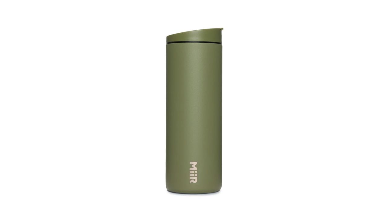 Green travel mug placed against white background.