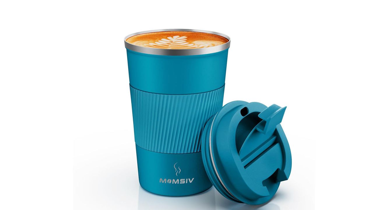 Open blue travel mug filled with latte inside and lid placed against the base. 
