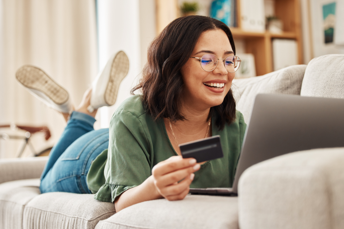 Woman on couch with laptop online shopping with credit card