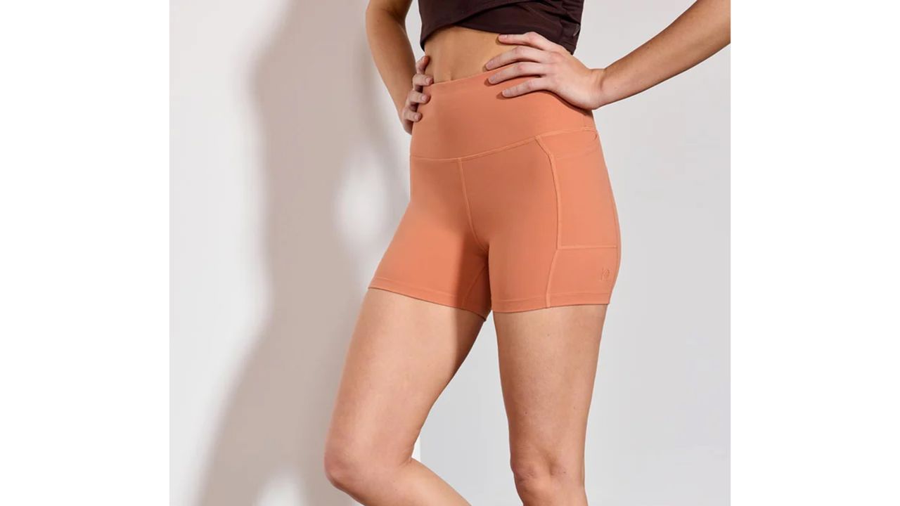 Woman wearing MPG Sport high-waisted pocket shorts in the sunburn color