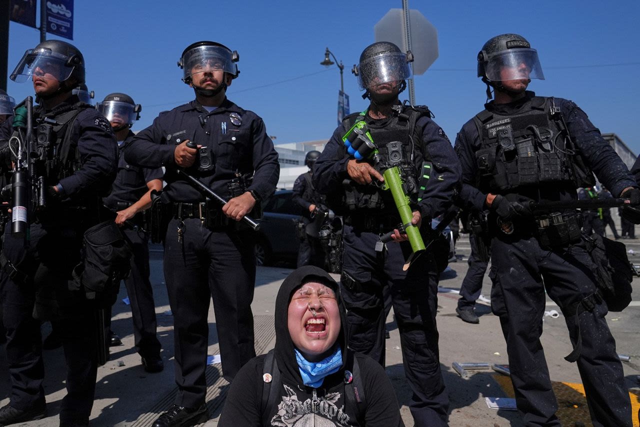 Una mujer grita mientras los manifestantes se enfrentan a una línea de policías cerca del Centro de Detención Metropolitano en el centro de Los Ángeles el domingo.