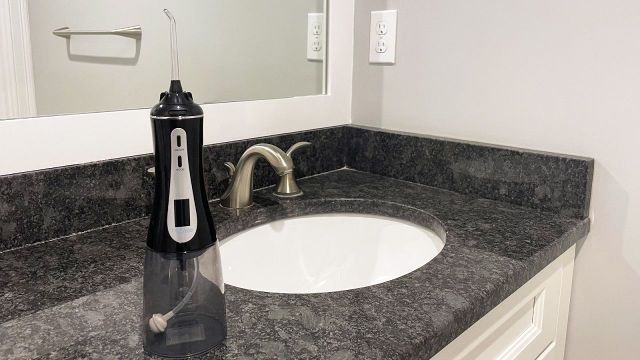 A MySmile Cordless Oral Irrigator on a marble bathroom counter, next to a sink