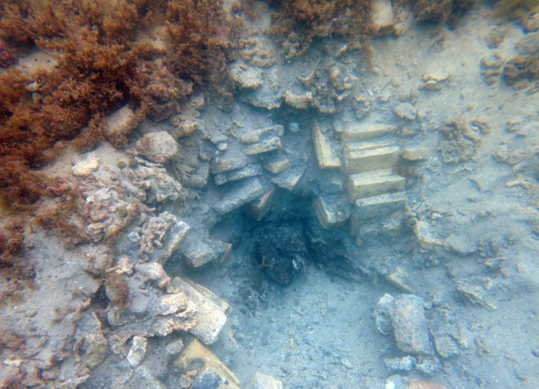 Imagen de un agujero excavado con ladrillos y madera visibles del naufragio.