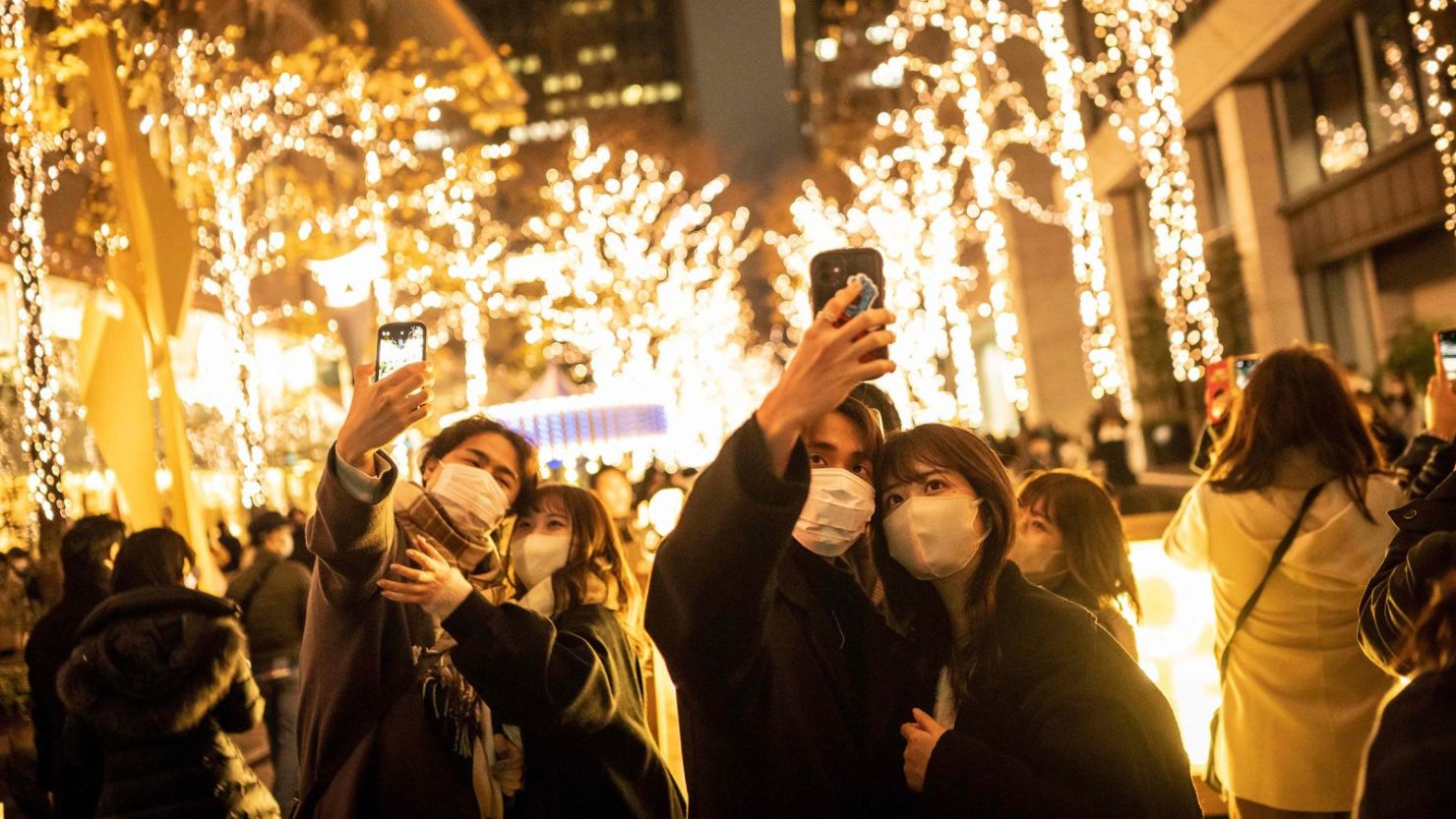 Las parejas se toman selfies en una calle con luces navideñas en Tokio el 25 de diciembre de 2022.